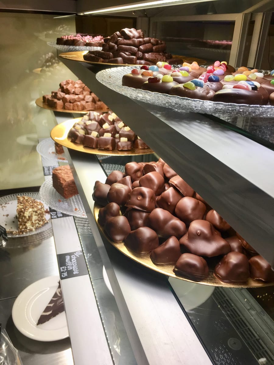 The chocolate display case: trays of heart truffles, chocolate-coated marshmallows, and slabs topped with coloured buttons.
