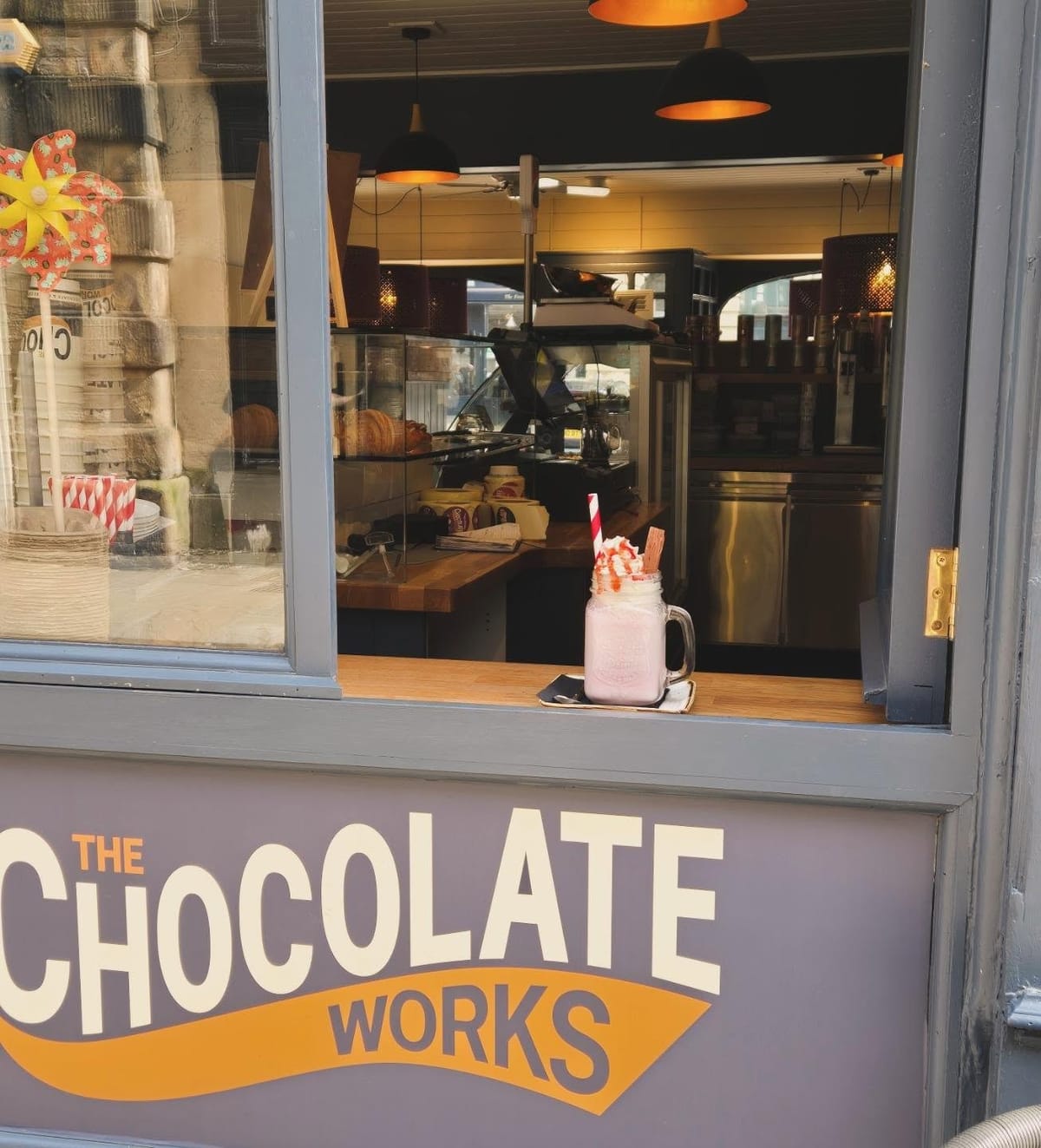 The painted shopfront on Castle Street, with a pink milkshake on the window ledge and the open kitchen visible behind the glass.